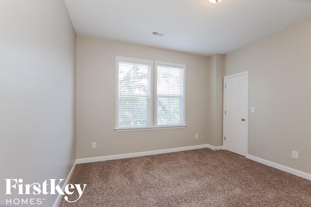 a bedroom with carpet and two windows and a door