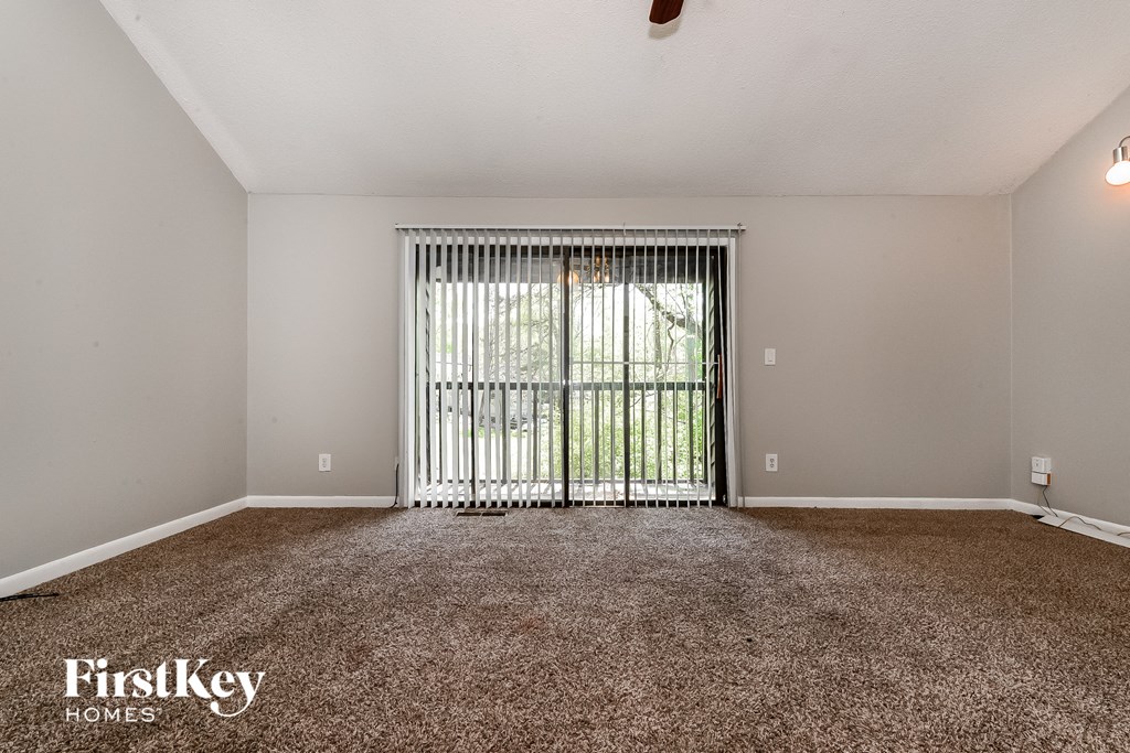the living room of an apartment with a large window and carpet