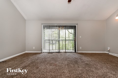 the living room of an apartment with a large window and carpet