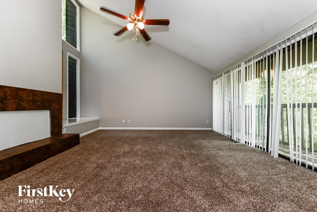 an empty living room with a ceiling fan and sliding glass doors