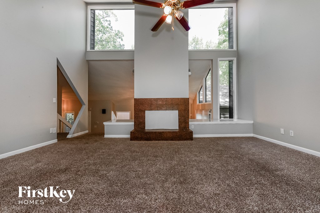 a living room with carpet and a ceiling fan