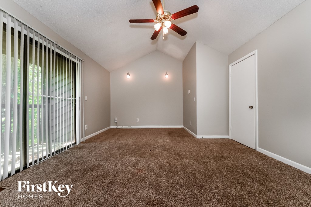 an empty living room with carpet and a ceiling fan