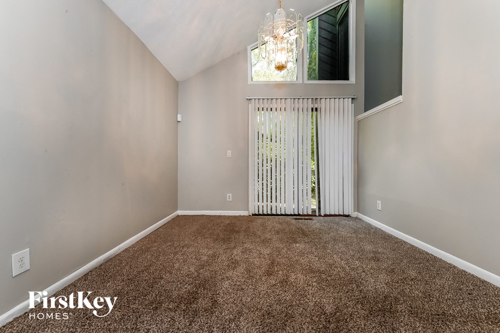 an empty living room with carpet and a door to a balcony