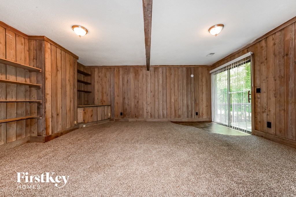 an empty living room with wood paneling and a sliding glass door