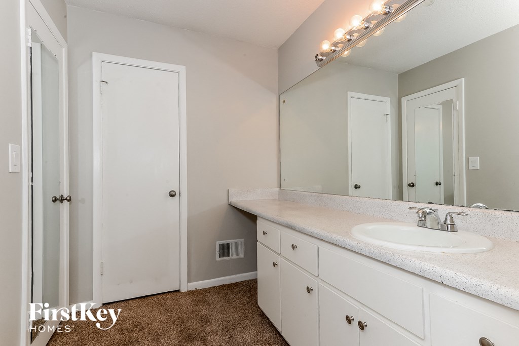 a bathroom with white cabinets and a sink and a mirror
