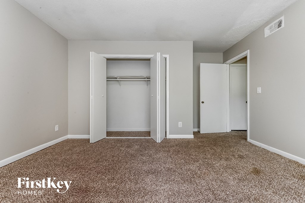 a bedroom with a closet and a carpeted floor