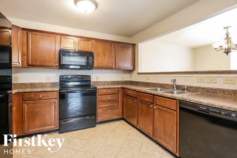 A kitchen with wooden cabinets and black appliances.