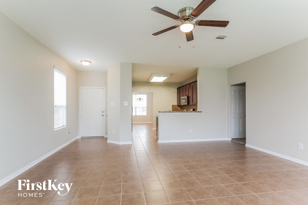 an empty living room and kitchen with a ceiling fan
