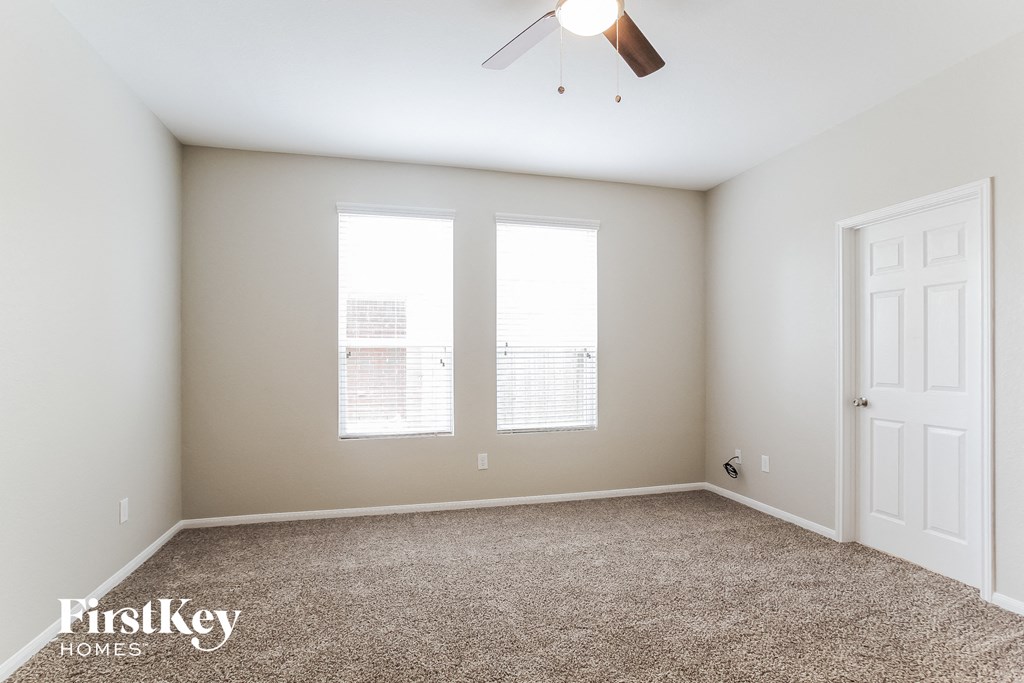 a empty room with two windows and a ceiling fan