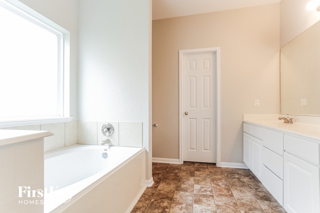 a bathroom with a tub and a sink and a window