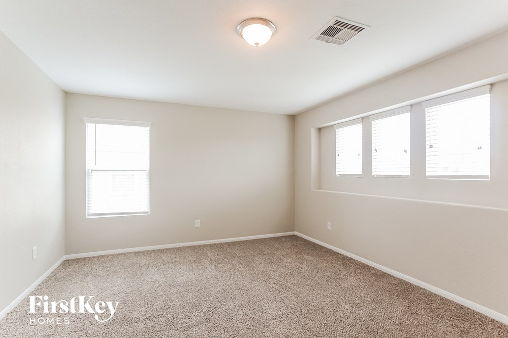 a bedroom with a carpeted floor and three windows