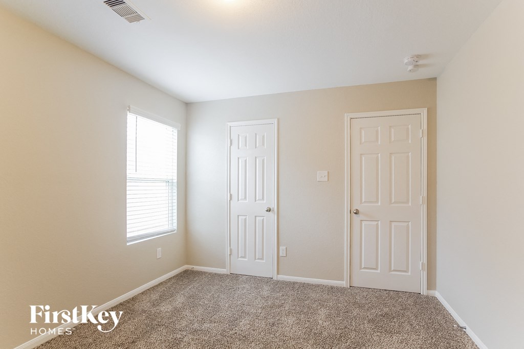 a bedroom with two doors and a carpeted floor and a window