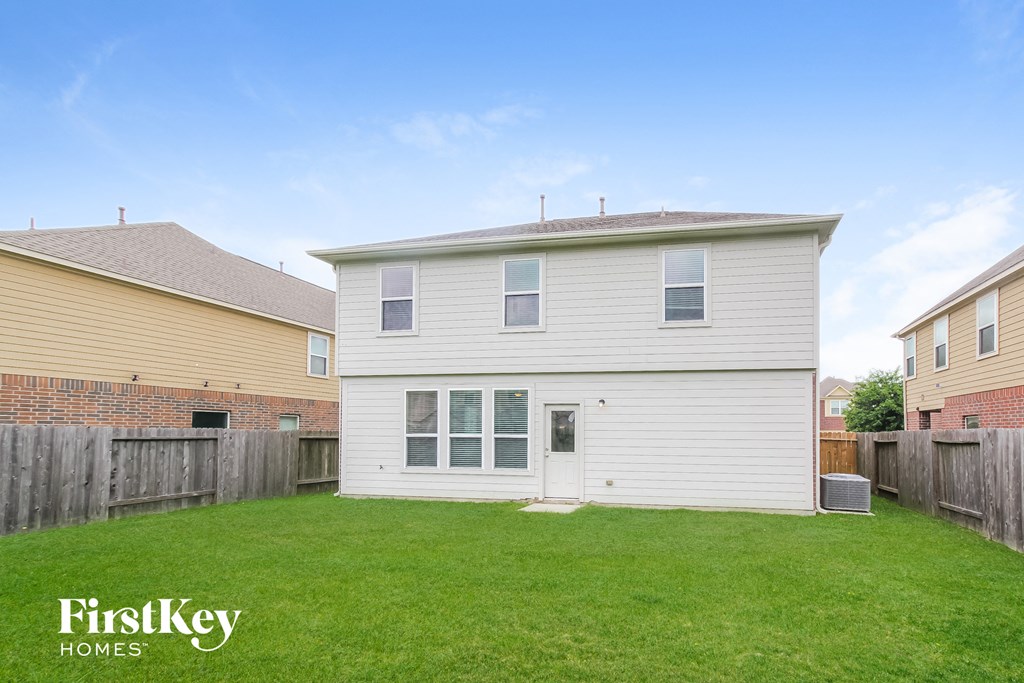 the backyard of a white house with a yard and a wooden fence