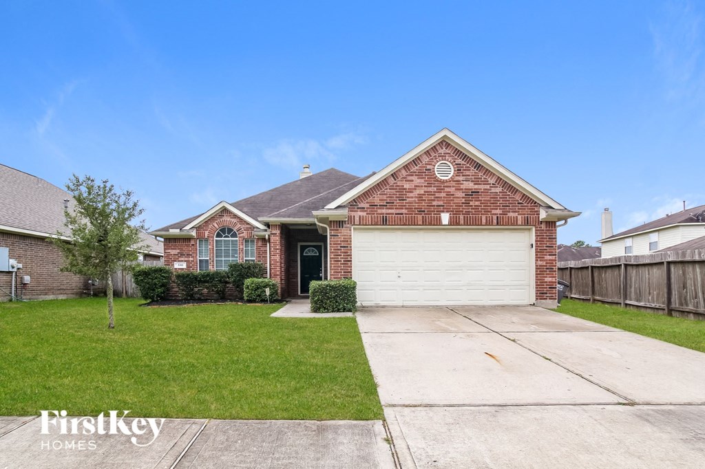 A brick house with a garage door is for sale.