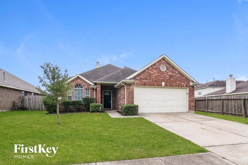 A brick house with a garage door is for sale.
