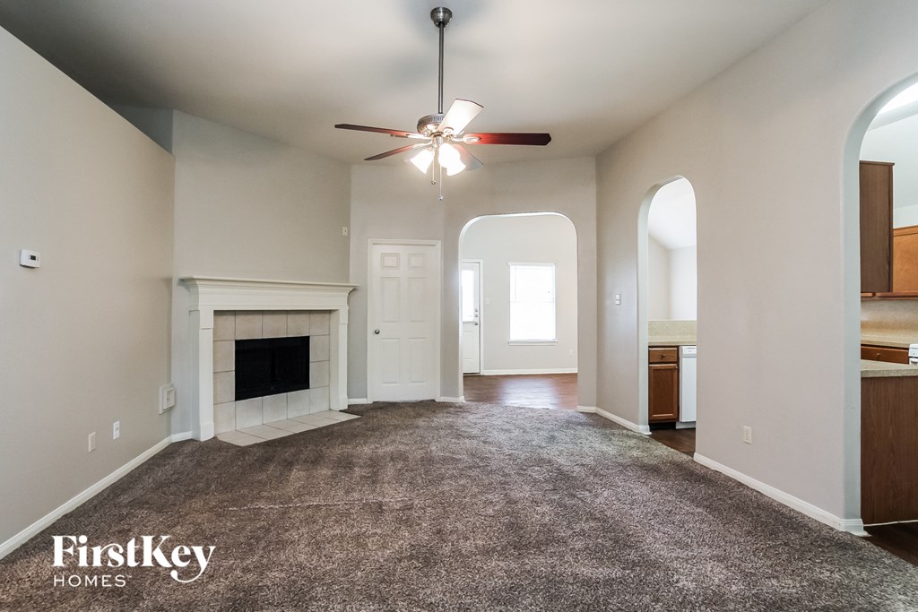 A spacious living room with a fireplace and a ceiling fan.