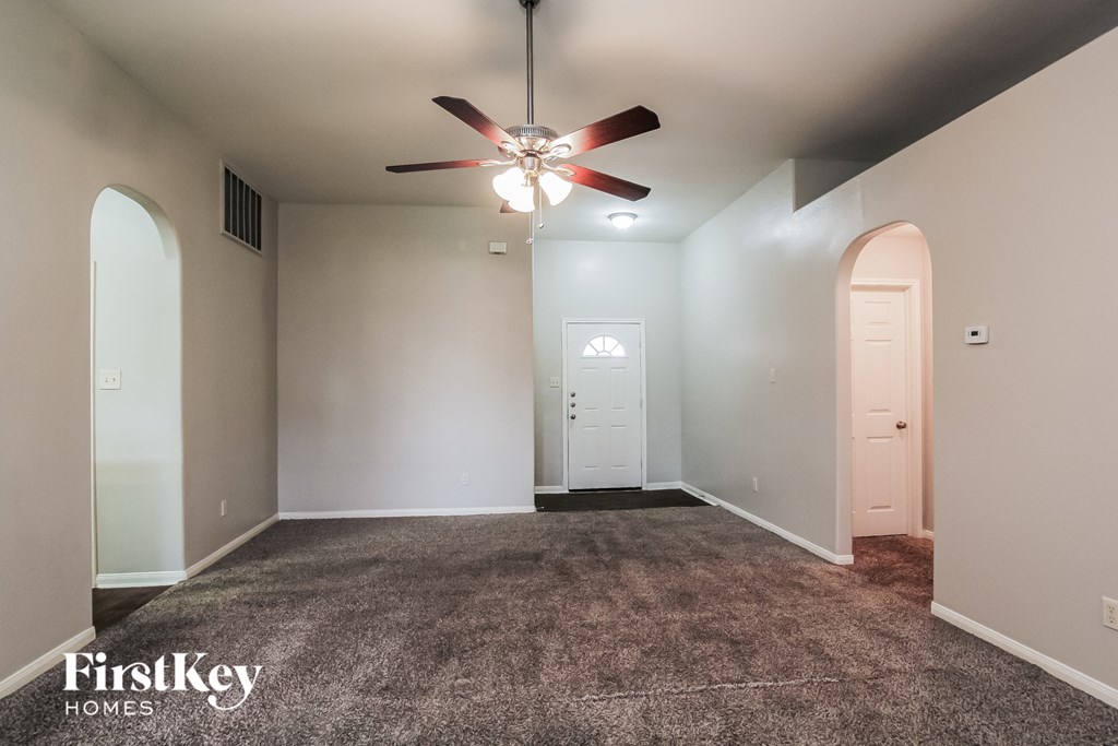 A spacious room with a carpeted floor and a ceiling fan.