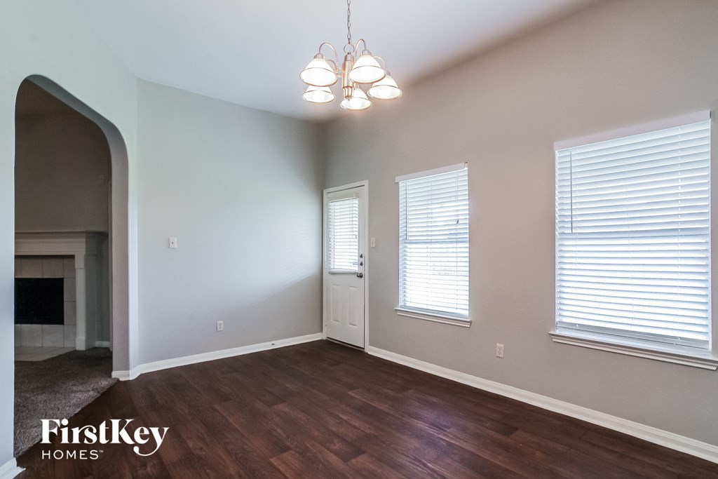 A room with wooden floors and a chandelier hanging from the ceiling.
