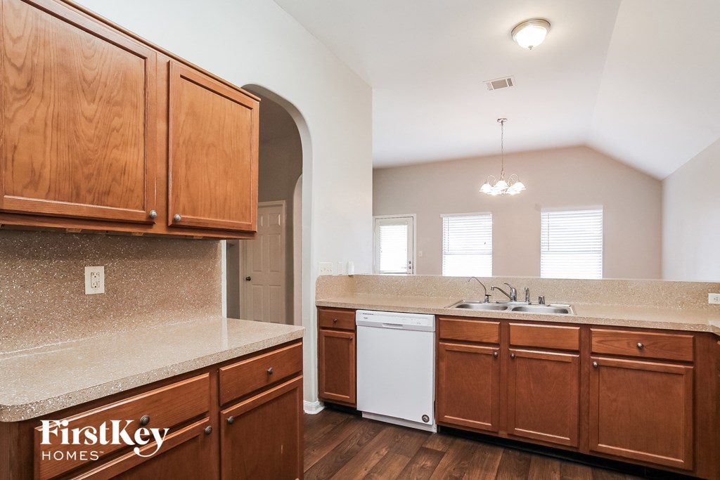 A kitchen with wooden cabinets and a white dishwasher.