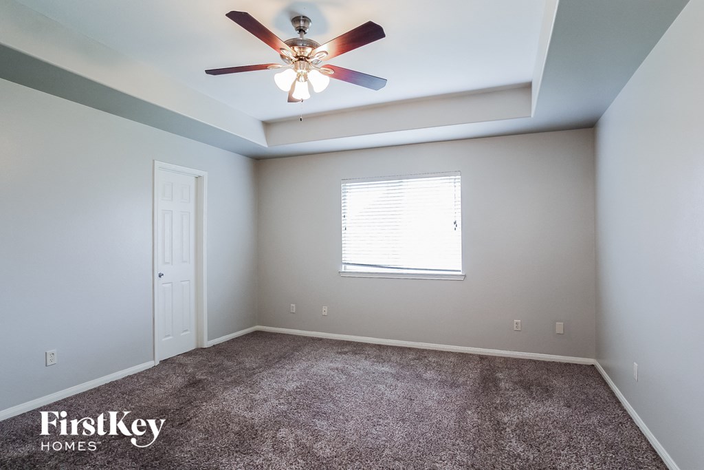 A room with a ceiling fan and a window with blinds.