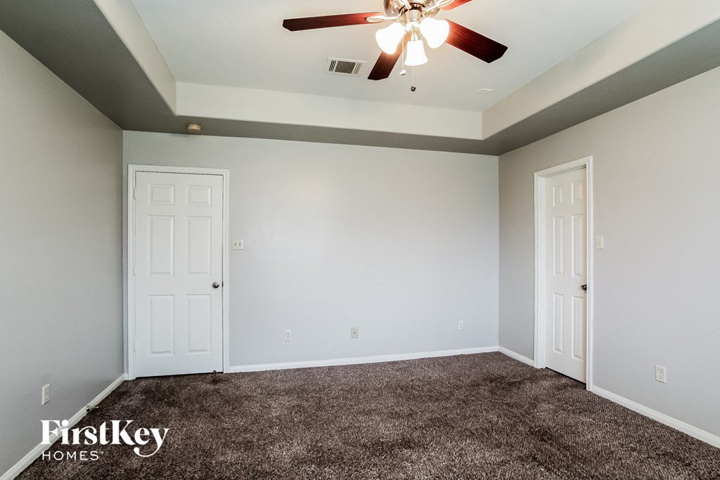 A room with a carpeted floor and a ceiling fan.