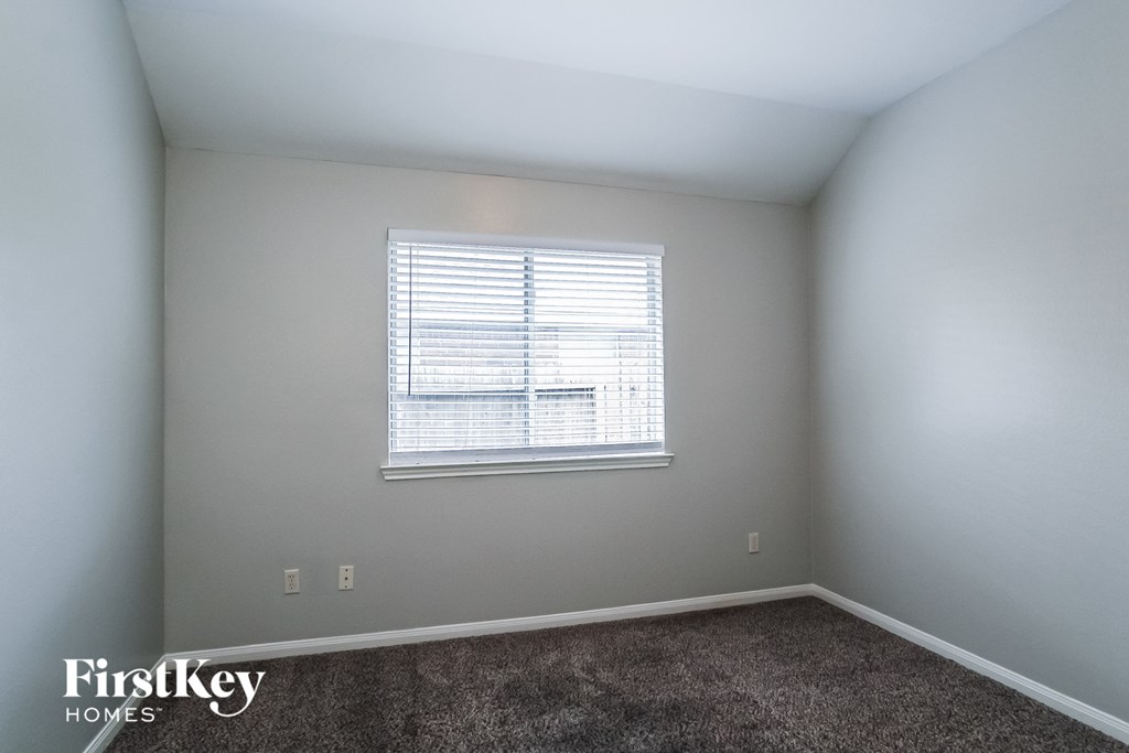 A room with a window and a carpeted floor.