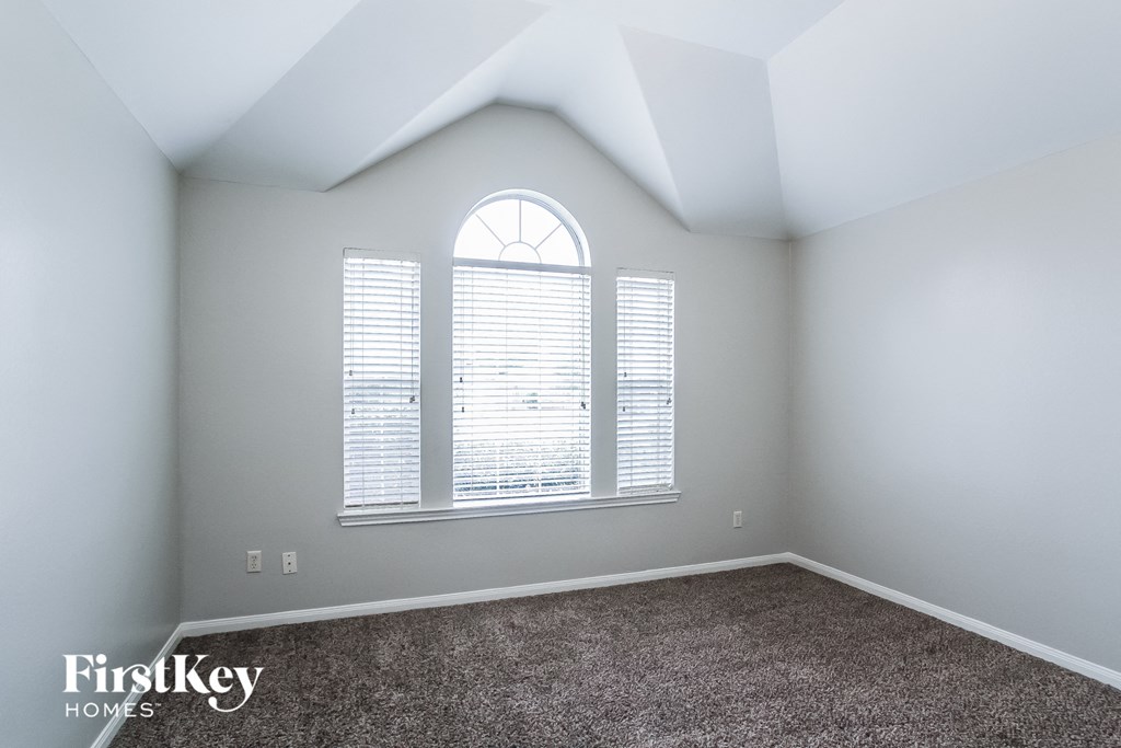 A room with a carpeted floor and a window with blinds.