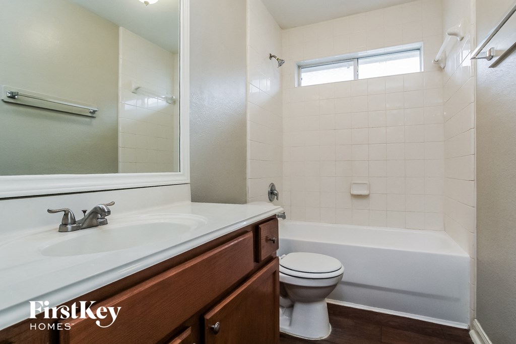 A white toilet sits in a bathroom with a white tub and a white sink.