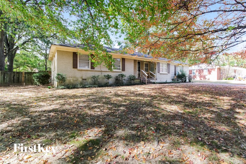 a small yellow house with a yard and trees