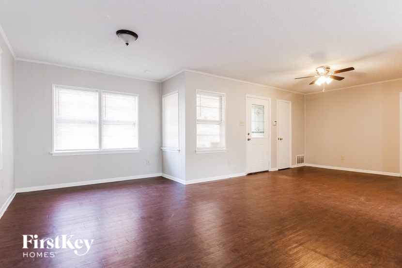 an empty living room with wood floors and a ceiling fan