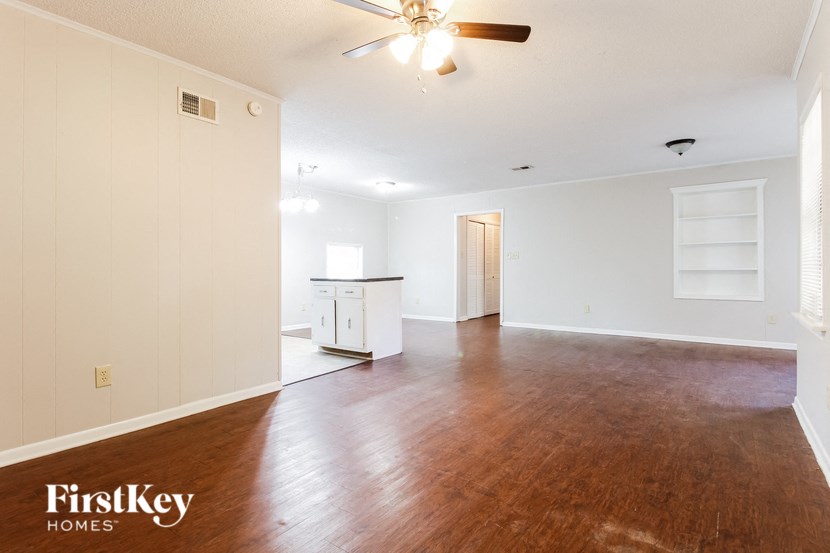 an empty living room with wood flooring and a ceiling fan
