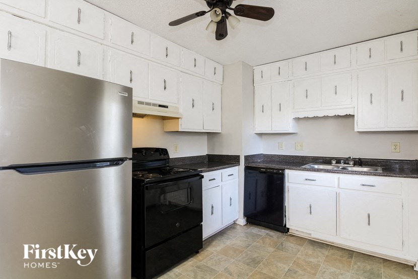 a white kitchen with black appliances and white cabinets