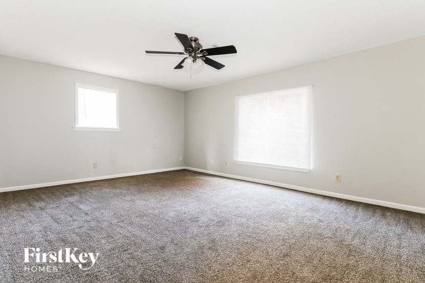 a living room with carpet and a ceiling fan