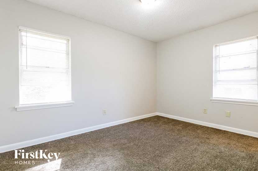 a bedroom with carpet and two windows