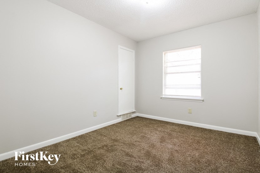 a carpeted room with a window and white walls