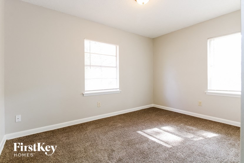 a room with carpet and two windows