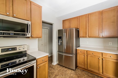 A kitchen with wooden cabinets and a stainless steel refrigerator.
