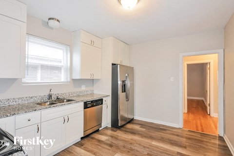 A kitchen with white cabinets and a stainless steel refrigerator.