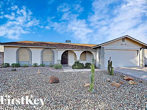 a house with a gravel driveway and a cactus