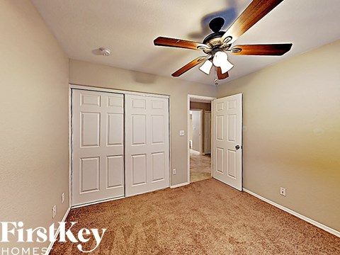 the master bedroom has a ceiling fan and a beige carpet