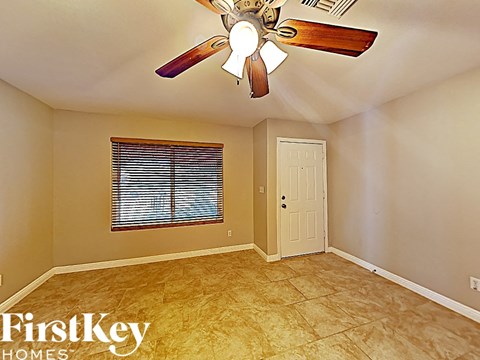 an empty living room with a ceiling fan and a door