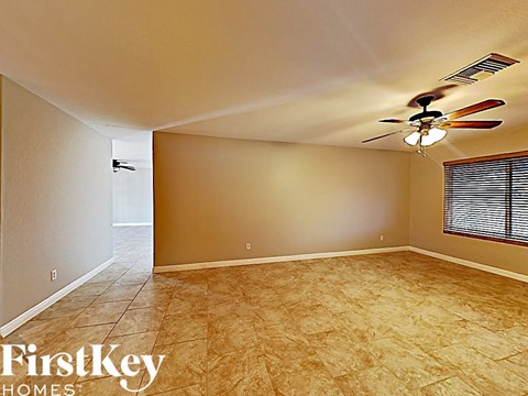 an empty living room with a ceiling fan and tile floor