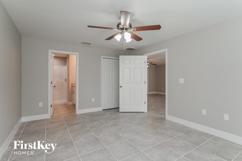 a living room with a ceiling fan and a door to a bathroom