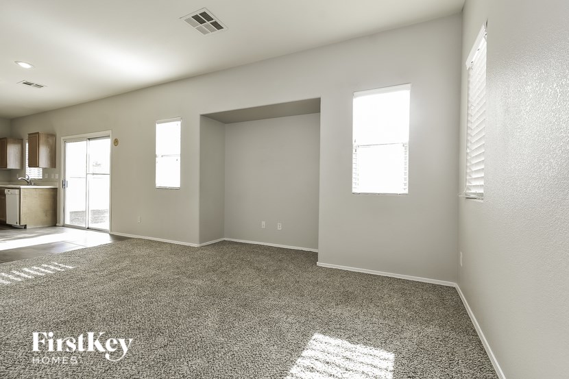 A spacious empty room with a carpet on the floor and a window on the wall.