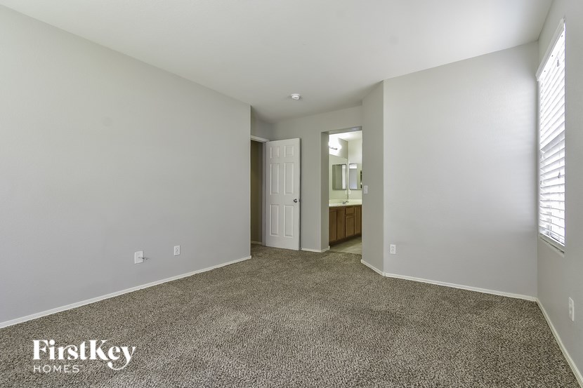 A spacious room with a carpeted floor and a doorway leading to another room.