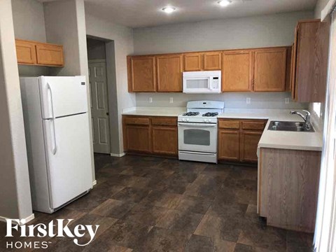 A kitchen with a white fridge, white microwave, white stove and white countertops.