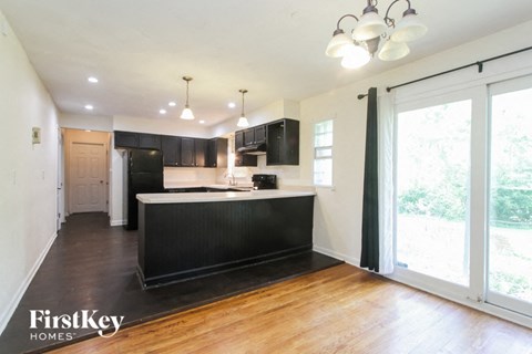 A kitchen with a black counter top and wooden floors.