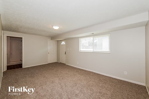 A spacious room with a carpeted floor and a window.