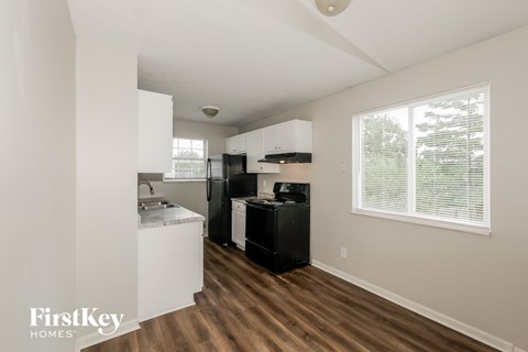 A kitchen with white cabinets and a black fridge.