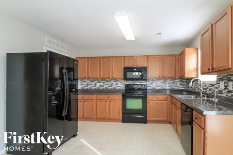 A kitchen with a black fridge and a black stove top oven.